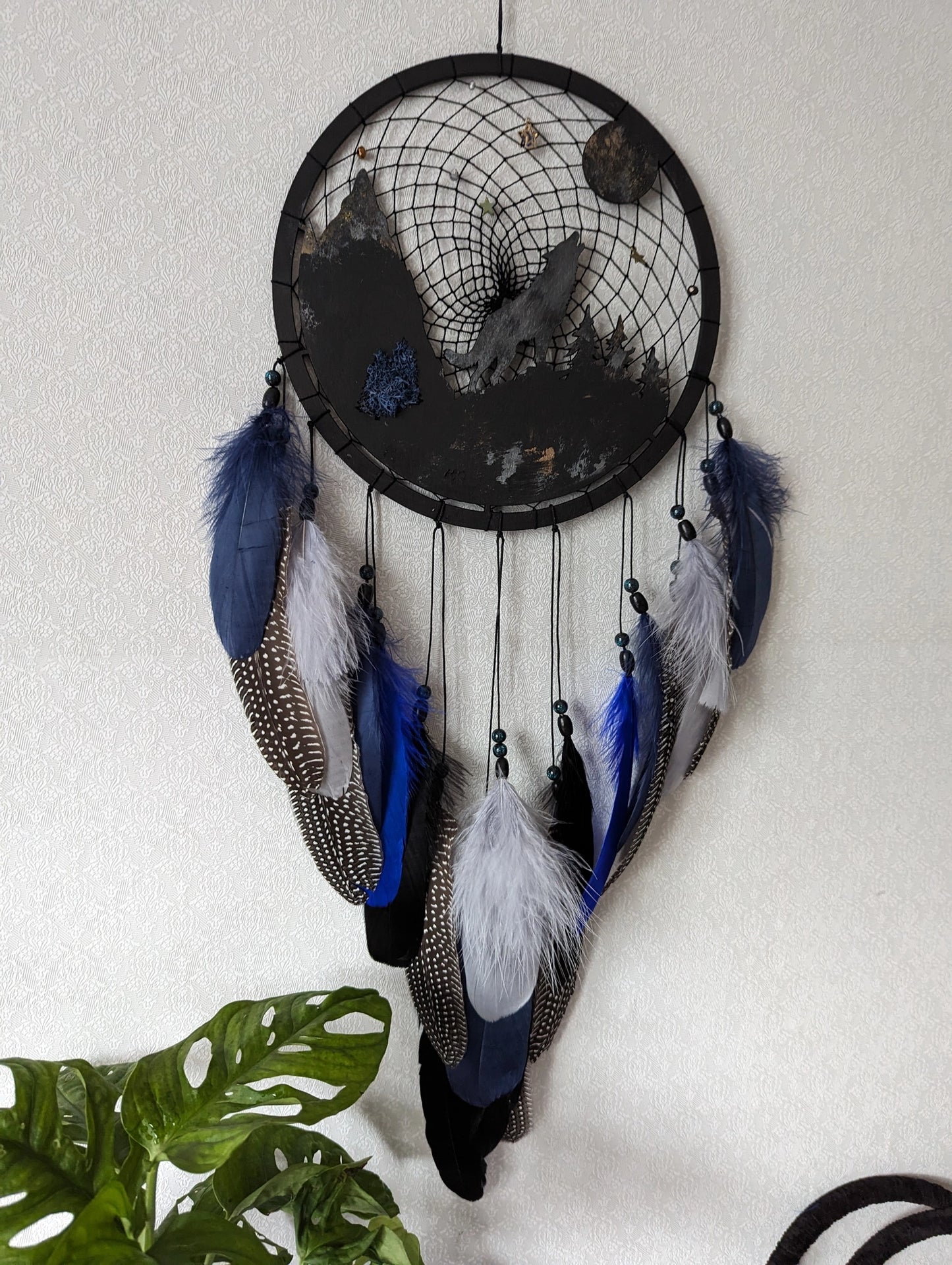 Handcrafted large black and blue wolf totem dreamcatcher with wooden wolf base, feathers, and webbing. Symbol of strength and guidance, perfect for nature-inspired spaces.