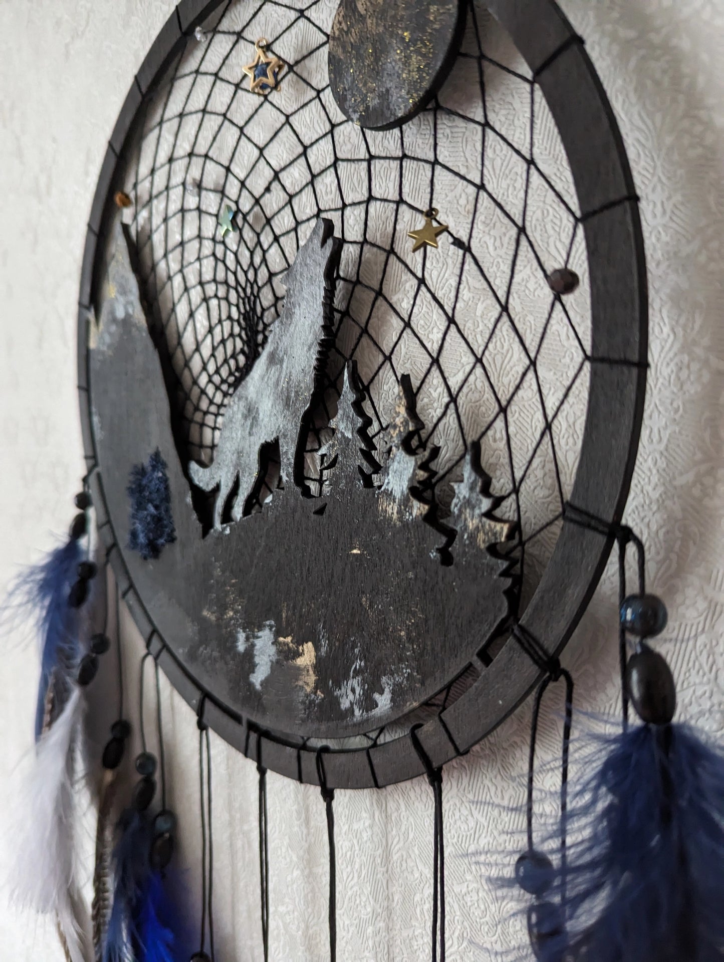 Handcrafted large black and blue wolf totem dreamcatcher with wooden wolf base, feathers, and webbing. Symbol of strength and guidance, perfect for nature-inspired spaces.