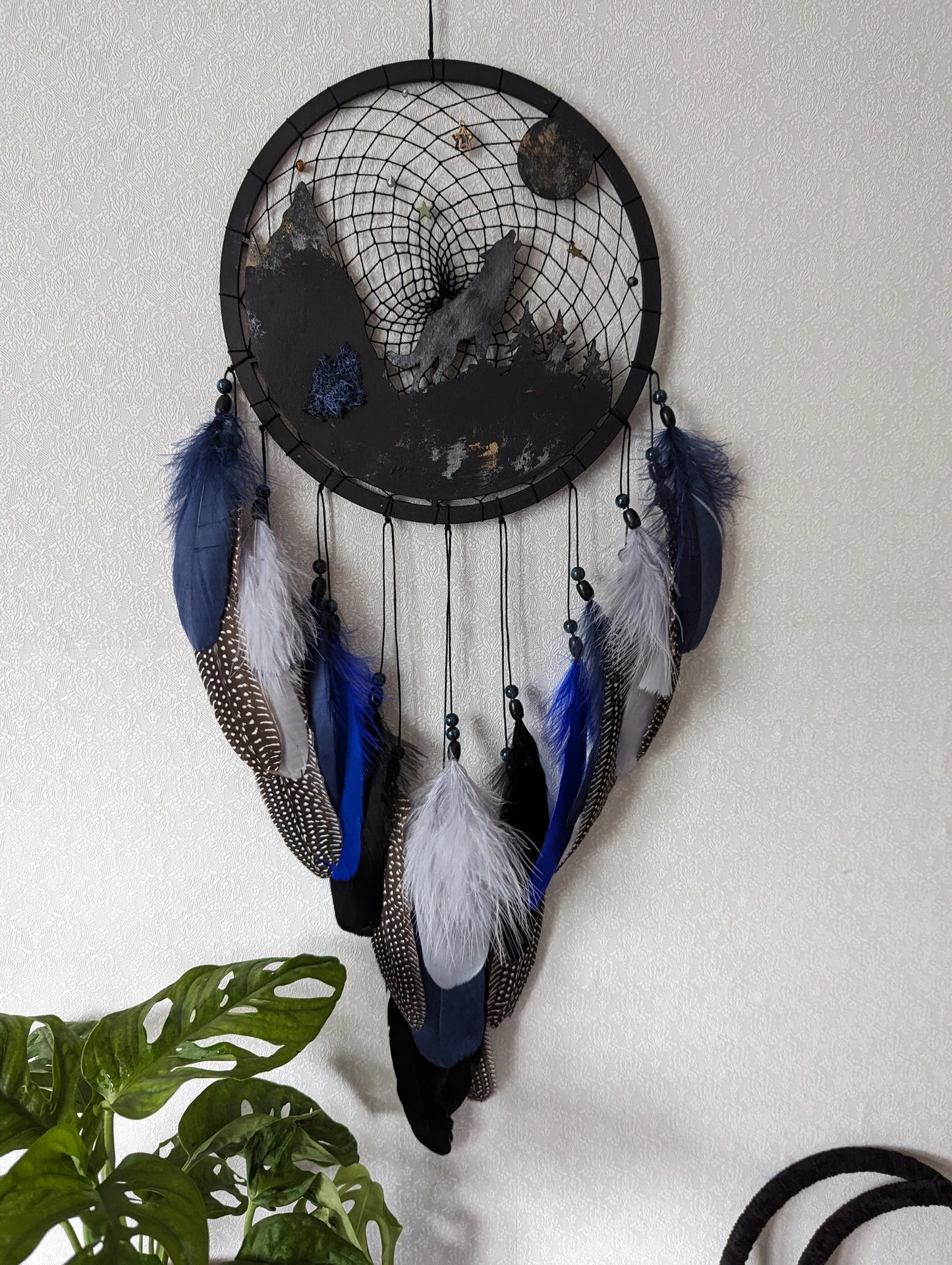Handcrafted large black and blue wolf totem dreamcatcher with wooden wolf base, feathers, and webbing. Symbol of strength and guidance, perfect for nature-inspired spaces.