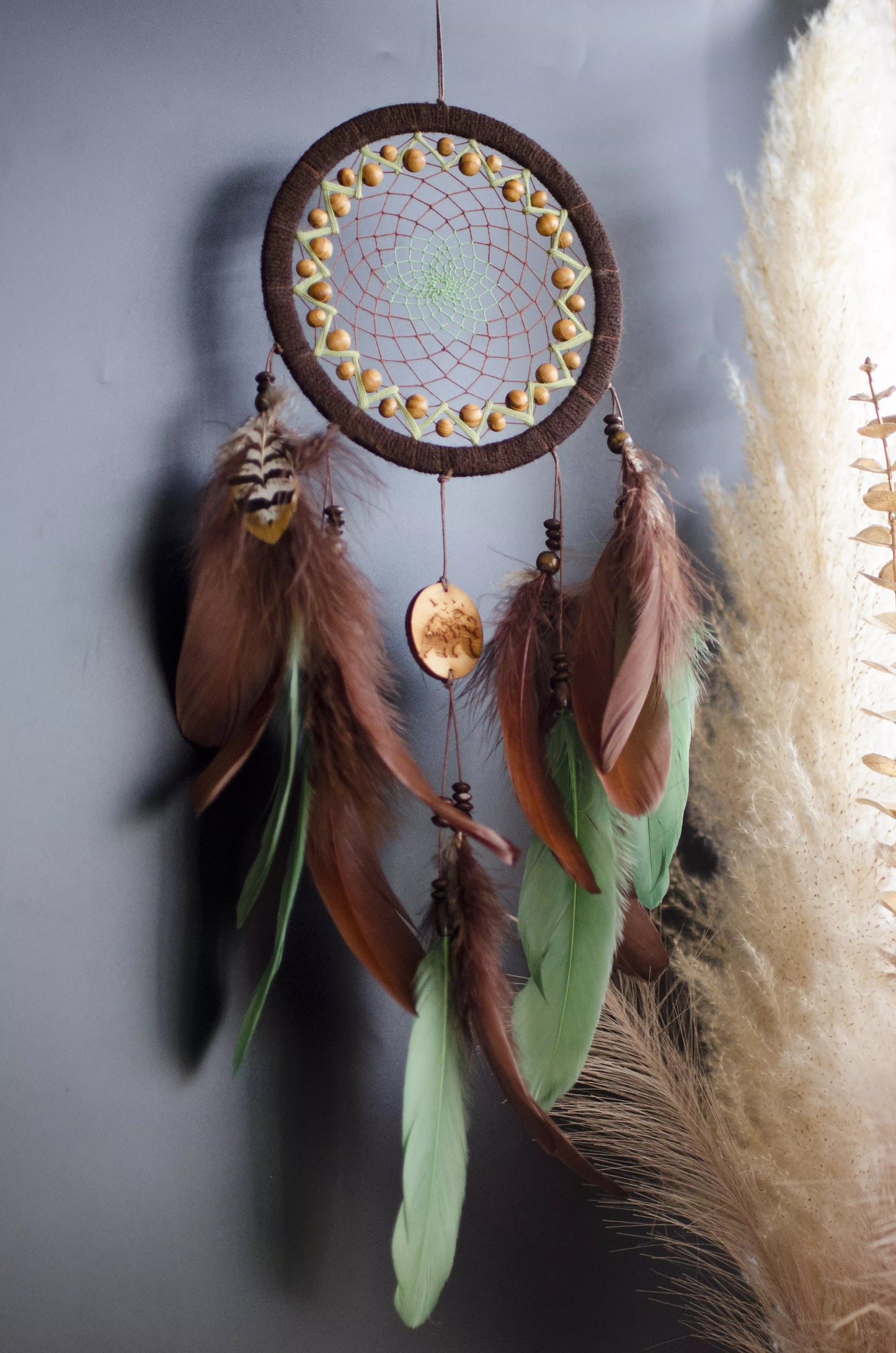 Handmade dream catcher with bear totem, rustic brown tones, feathers, and natural textures. Boho wall hanging for nature lovers and spiritual protection.