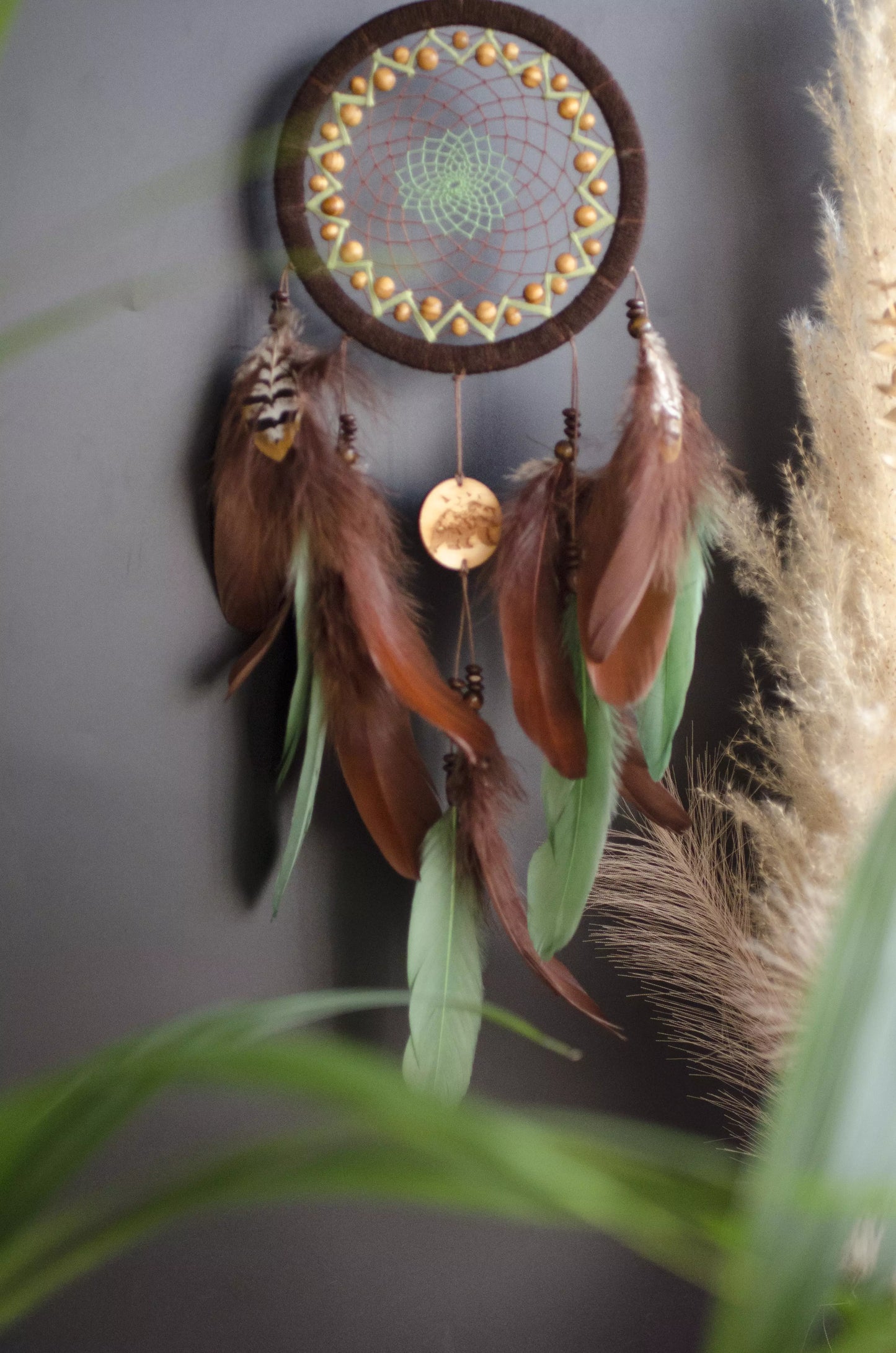 Handmade dream catcher with bear totem, rustic brown tones, feathers, and natural textures. Boho wall hanging for nature lovers and spiritual protection.