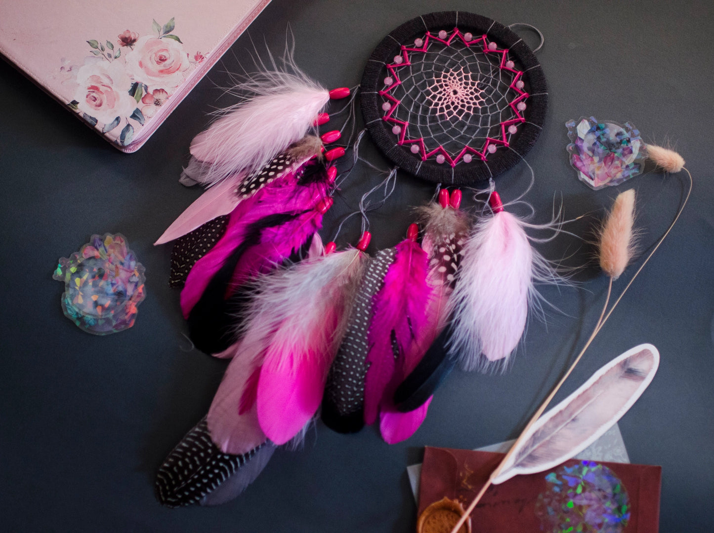 Handmade dreamcatcher in vibrant pink and black with bold feathers and woven web. Striking contrast for expressive, edgy spaces.