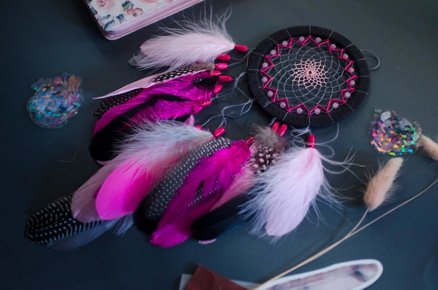 Handmade dreamcatcher in vibrant pink and black with bold feathers and woven web. Striking contrast for expressive, edgy spaces.