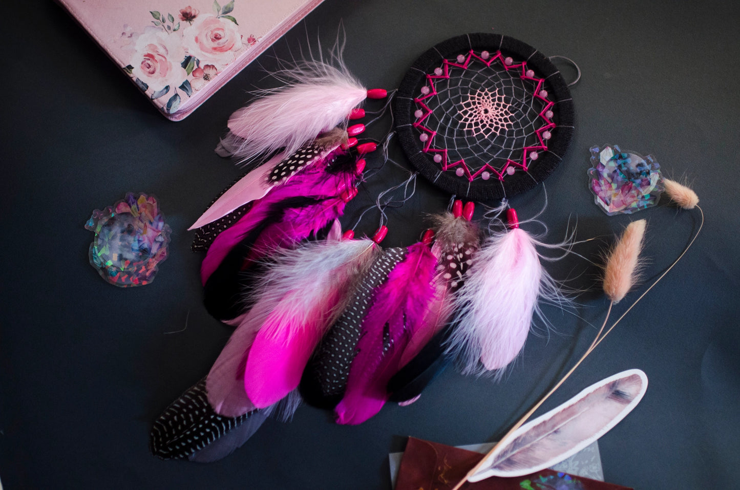 Handmade dreamcatcher in vibrant pink and black with bold feathers and woven web. Striking contrast for expressive, edgy spaces.