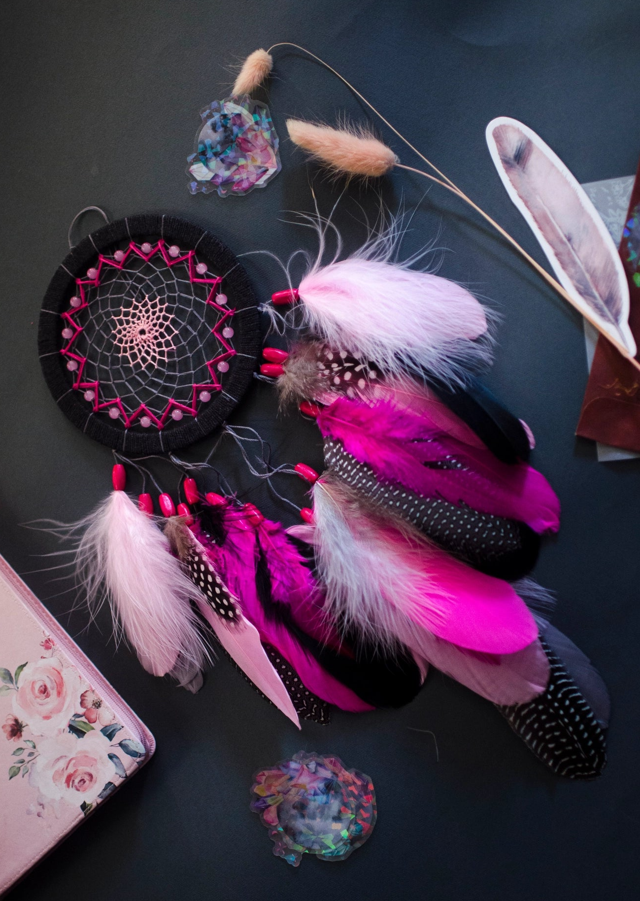 Handmade dreamcatcher in vibrant pink and black with bold feathers and woven web. Striking contrast for expressive, edgy spaces.