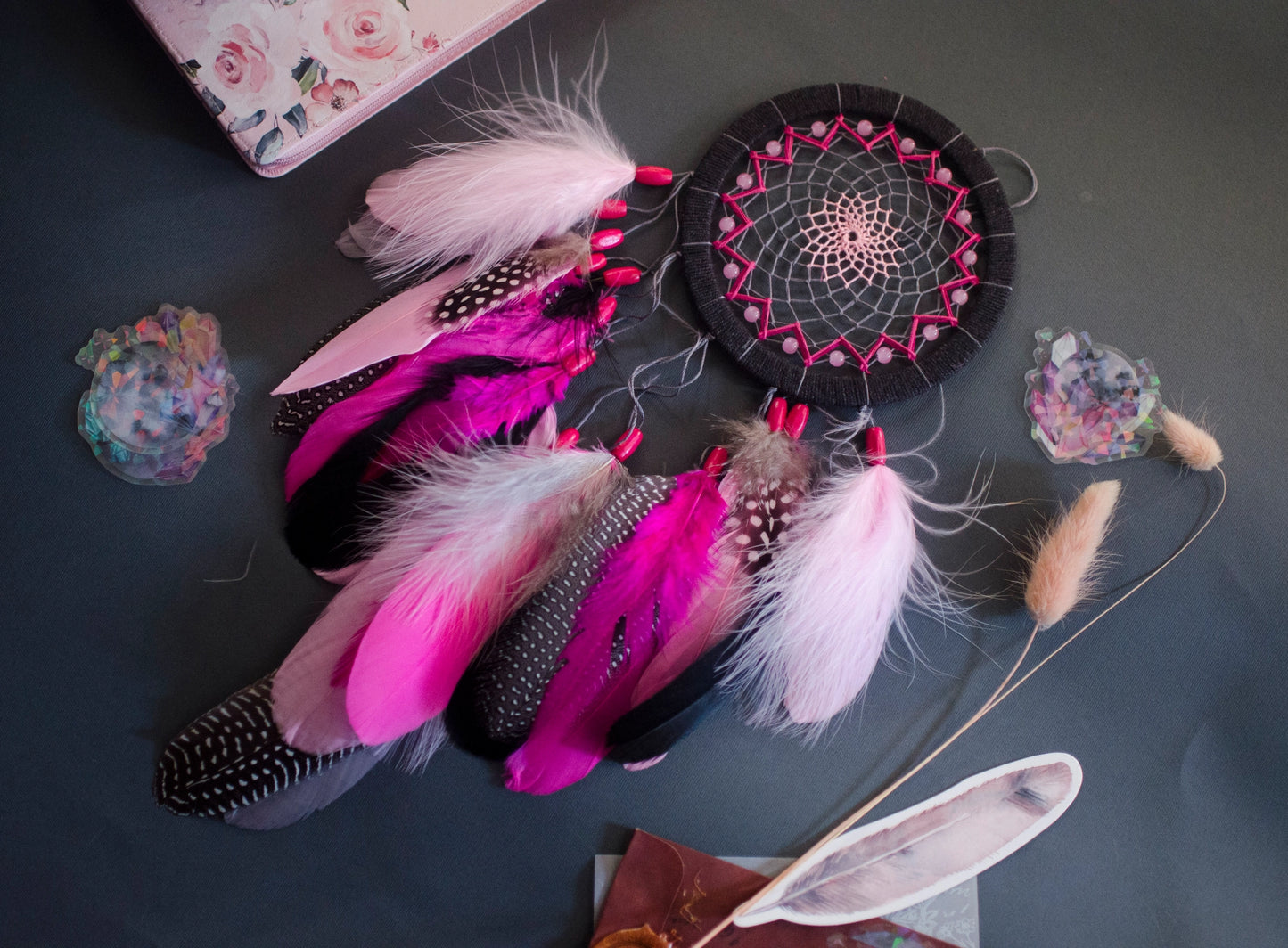 Handmade dreamcatcher in vibrant pink and black with bold feathers and woven web. Striking contrast for expressive, edgy spaces.