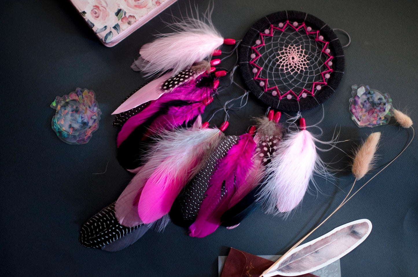 Handmade dreamcatcher in vibrant pink and black with bold feathers and woven web. Striking contrast for expressive, edgy spaces.