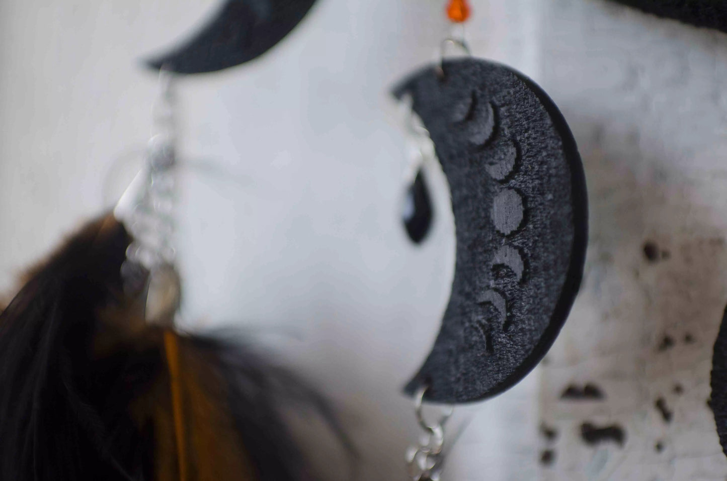 Handcrafted black dream catcher featuring an intricate web design with crescent moon charms and vibrant orange feathers. This bohemian wall decor piece is perfect for capturing negative dreams and channeling positive energy. Ideal for enhancing the aesthetic of any home or office space and makes a thoughtful, spiritual gift.