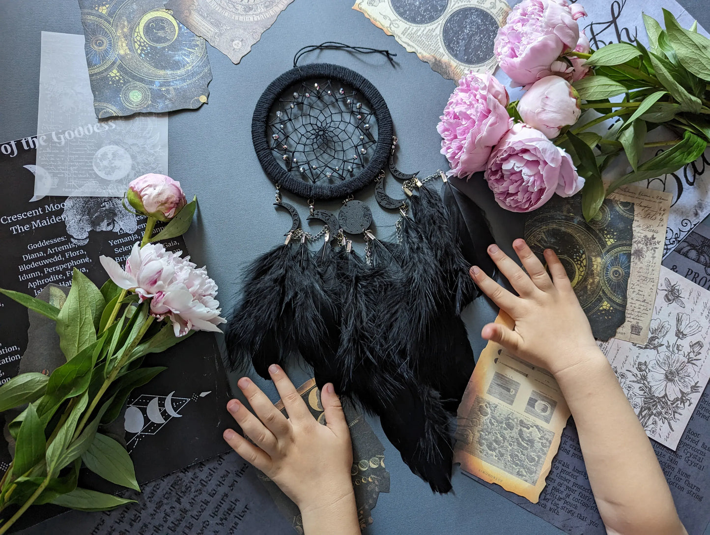 Handcrafted black dream catcher featuring a central web with black beads, adorned with five crescent moons and a central full moon, complemented by lush black feathers.