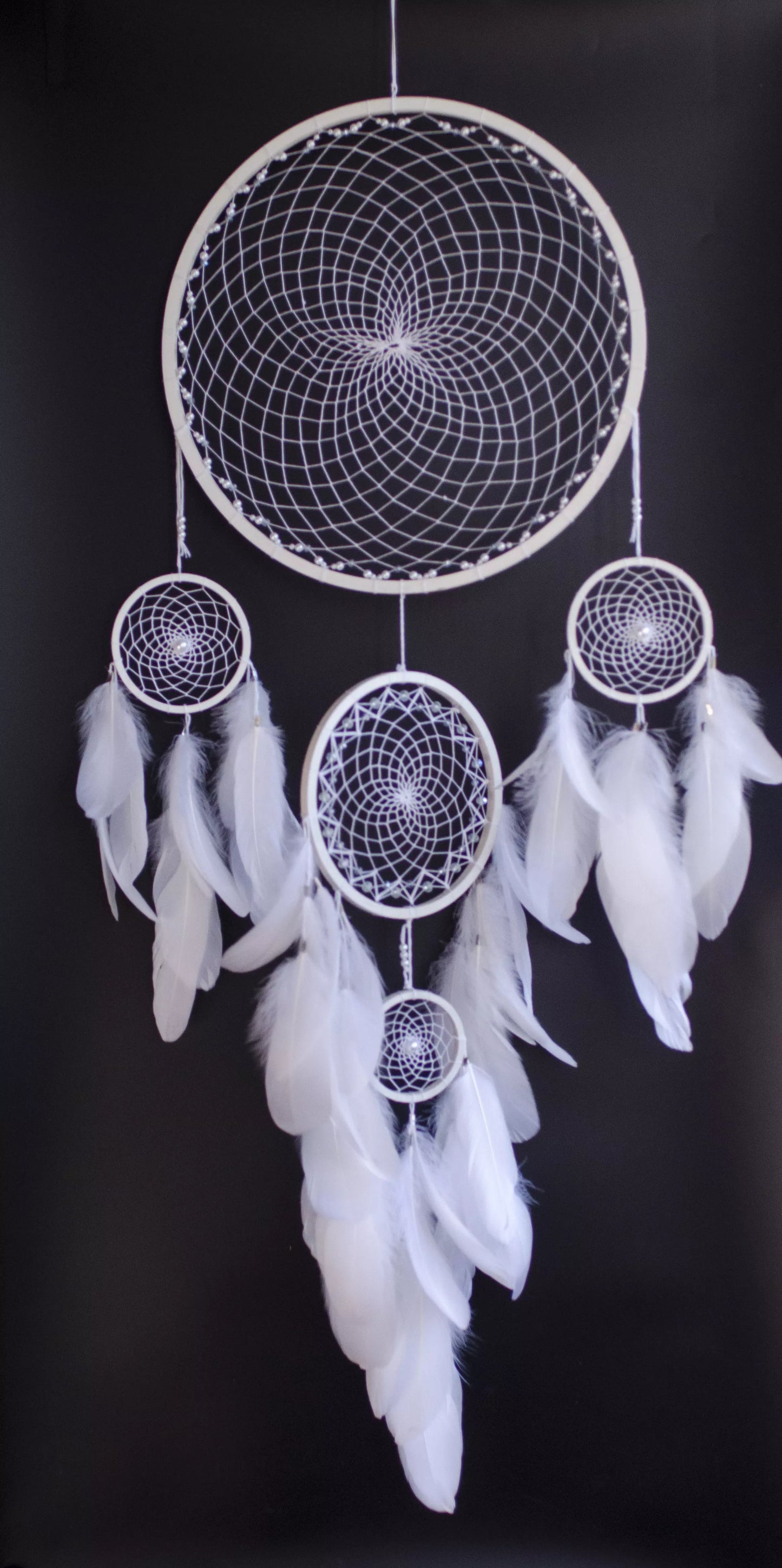 Handmade dreamcatcher with intricate web design, available in white or black, featuring hanging elements and two size options—standard and XL—perfect for boho or spiritual home decor.