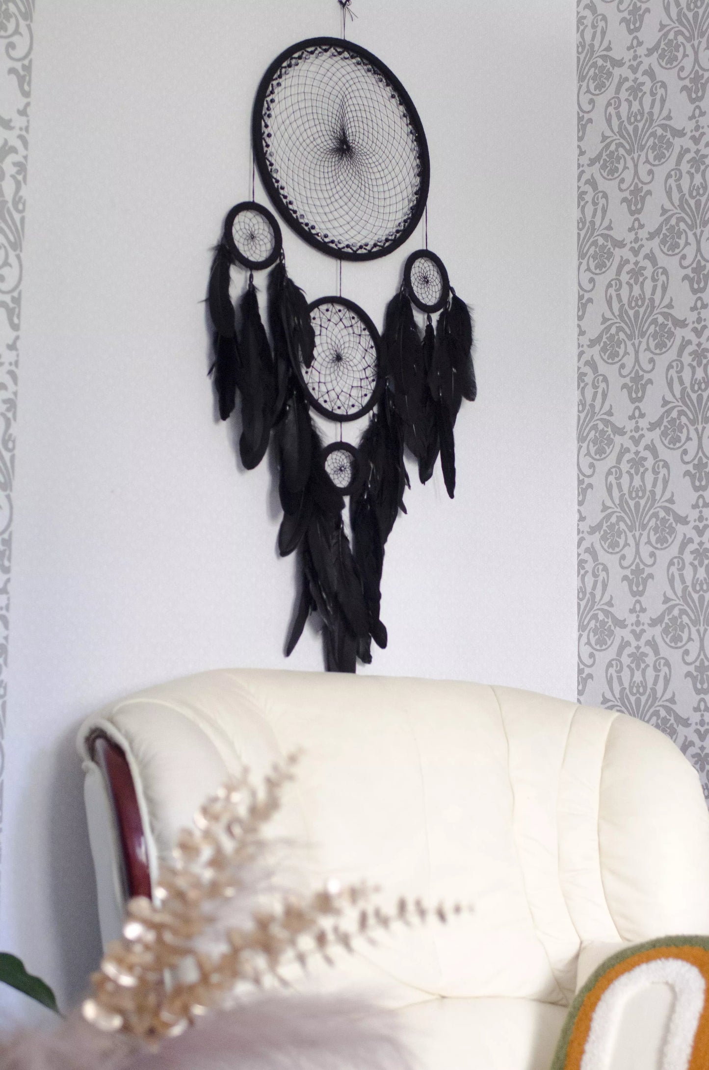 Large black multi-ring dreamcatcher featuring intricate woven web and cascading black feathers. Handcrafted boho and gothic wall decor, perfect for adding a statement piece to bedrooms or living rooms. Measures approximately 40 inches in height.