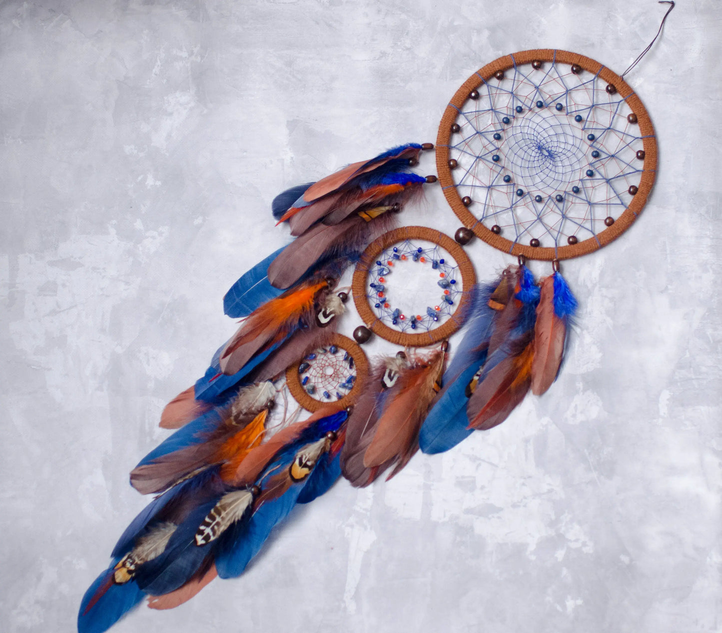 Large handmade dreamcatcher with blue and brown feathers, wooden hoops, and beaded web — boho wall hanging