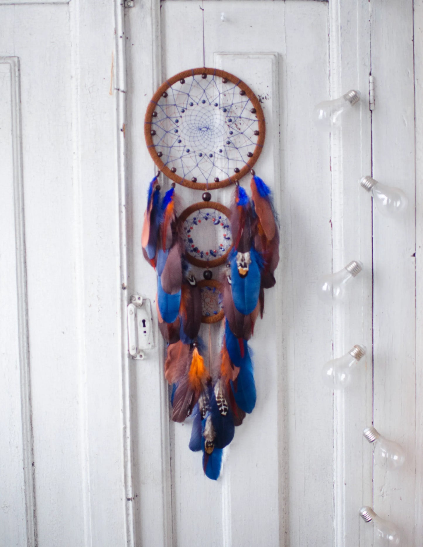 Large handmade dreamcatcher with blue and brown feathers, wooden hoops, and beaded web — boho wall hanging