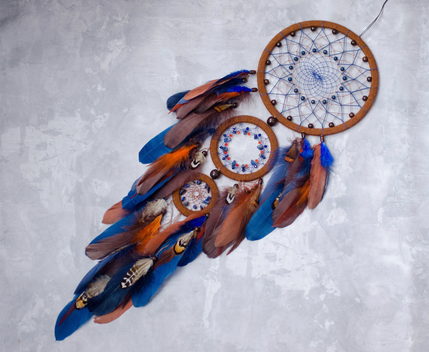 Large handmade dreamcatcher with blue and brown feathers, wooden hoops, and beaded web — boho wall hanging