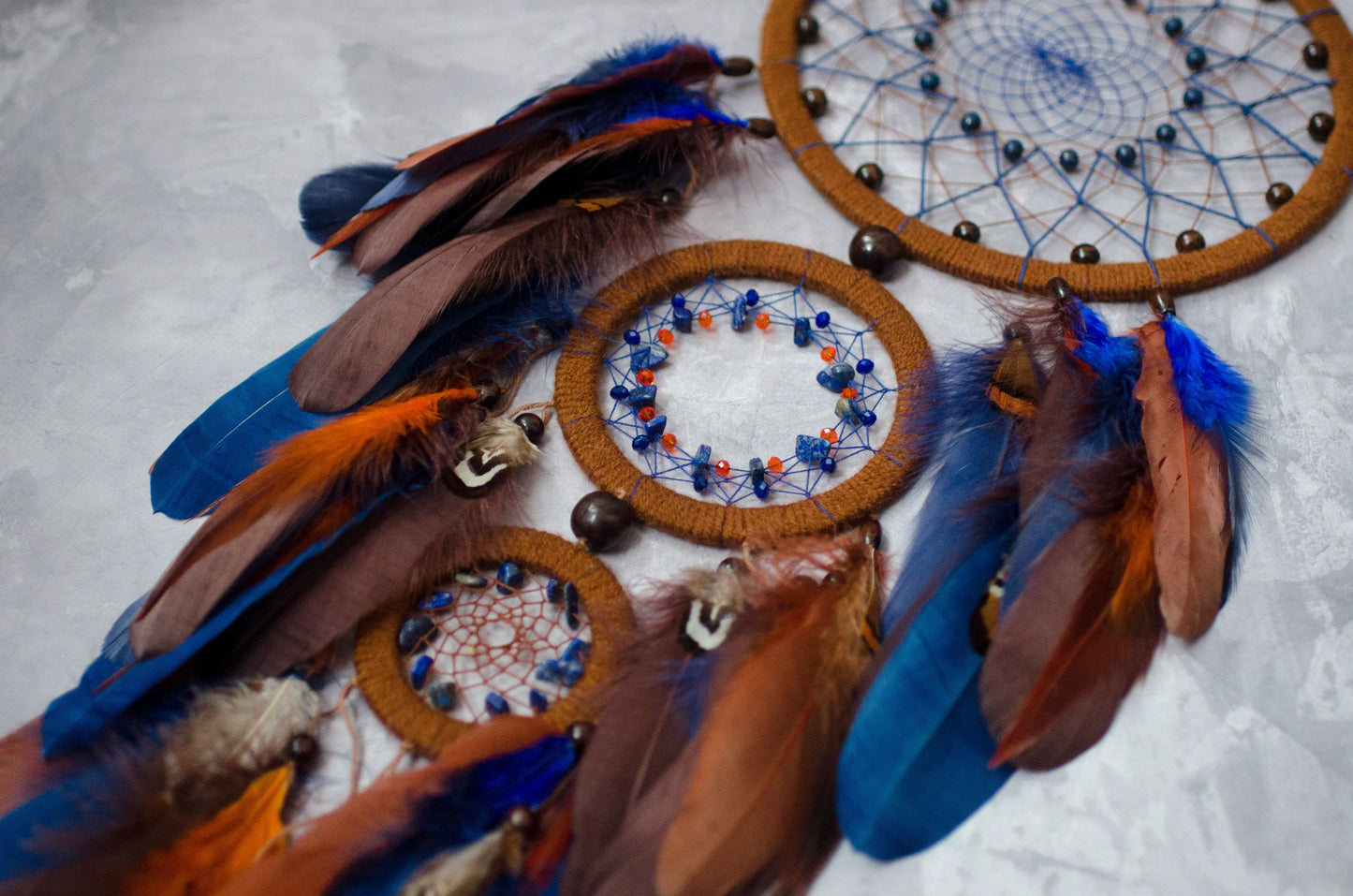 Large handmade dreamcatcher with blue and brown feathers, wooden hoops, and beaded web — boho wall hanging