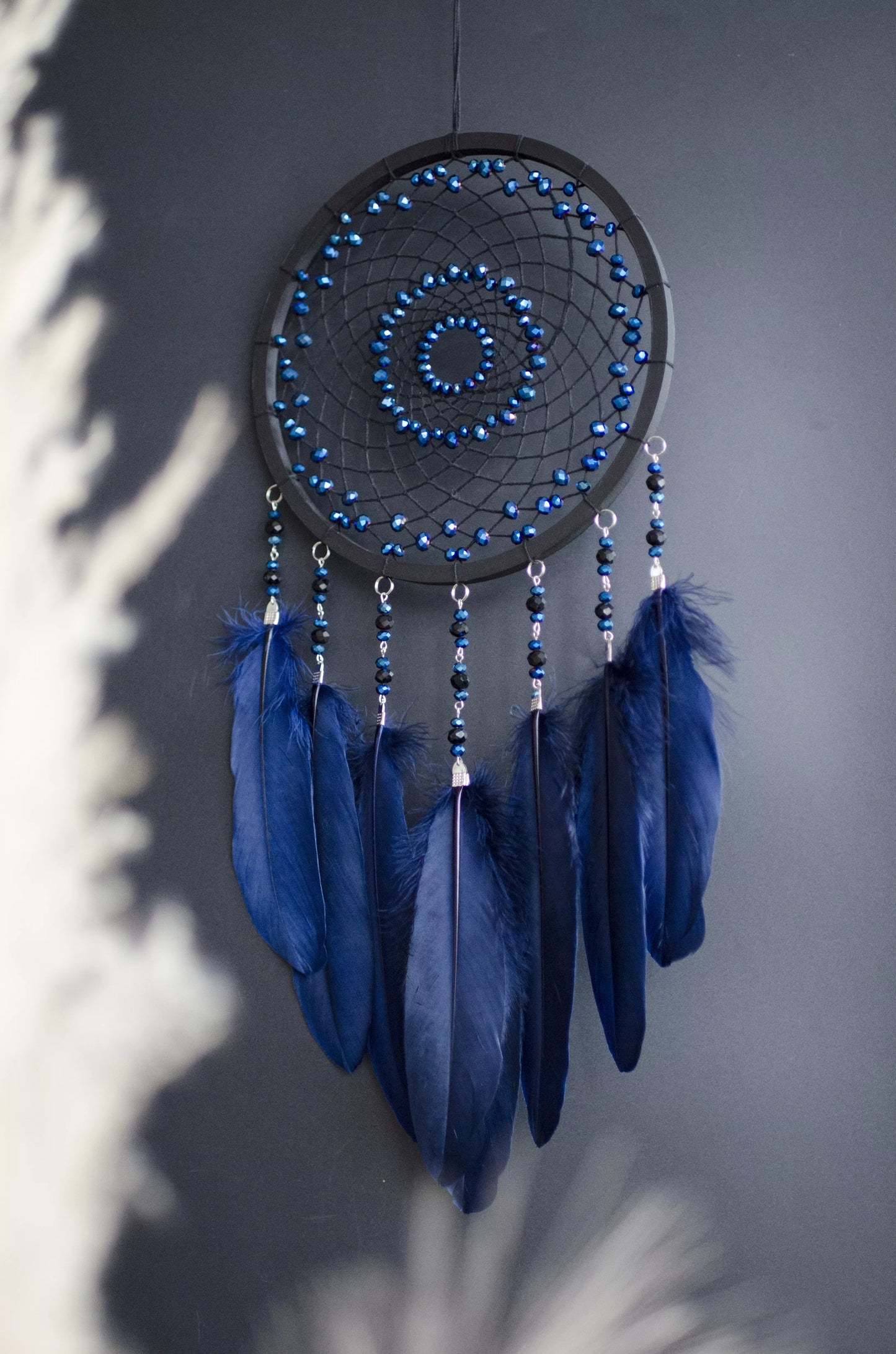 Handmade blue triple moon dreamcatcher set with navy feathers and moon phase design. Boho wall hanging for bedroom or nursery, offering celestial charm and symbolic protection.
