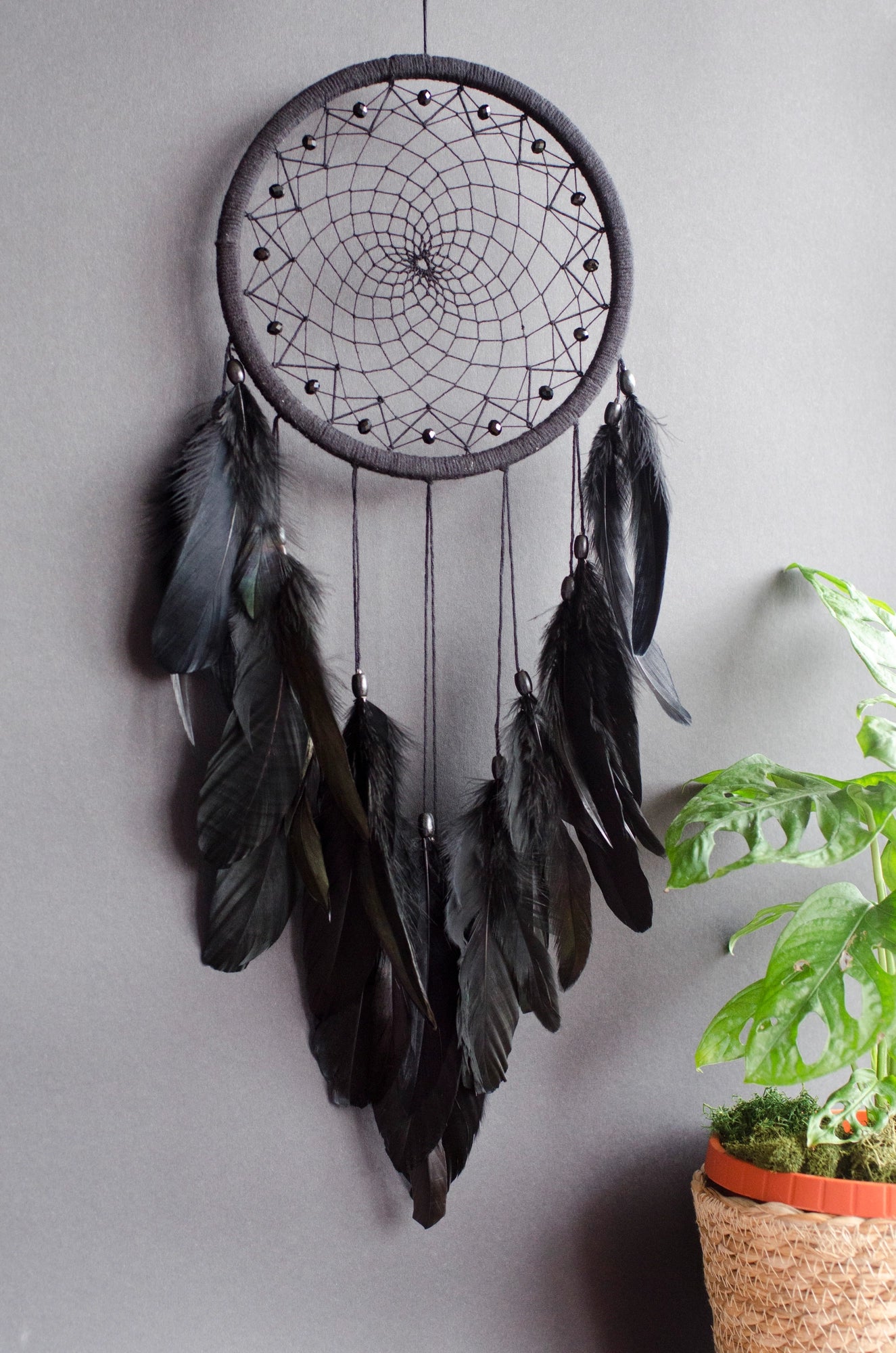 Handmade dreamcatcher with intricate web design, available in white or black, featuring hanging elements and two size options—standard and XL—perfect for boho or spiritual home decor.