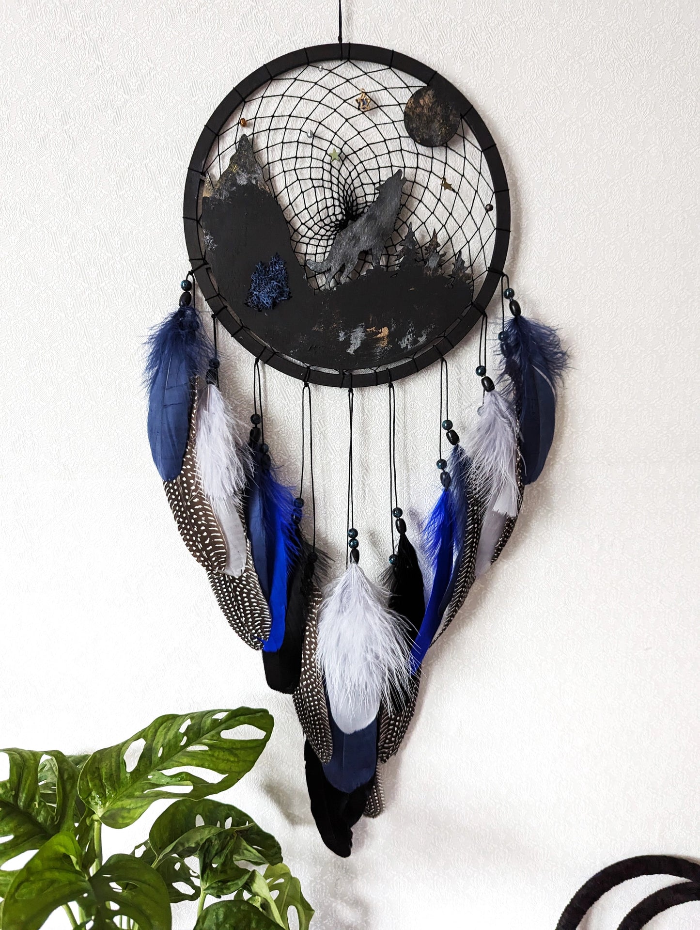 Handcrafted large black and blue wolf totem dreamcatcher with wooden wolf base, feathers, and webbing. Symbol of strength and guidance, perfect for nature-inspired spaces.