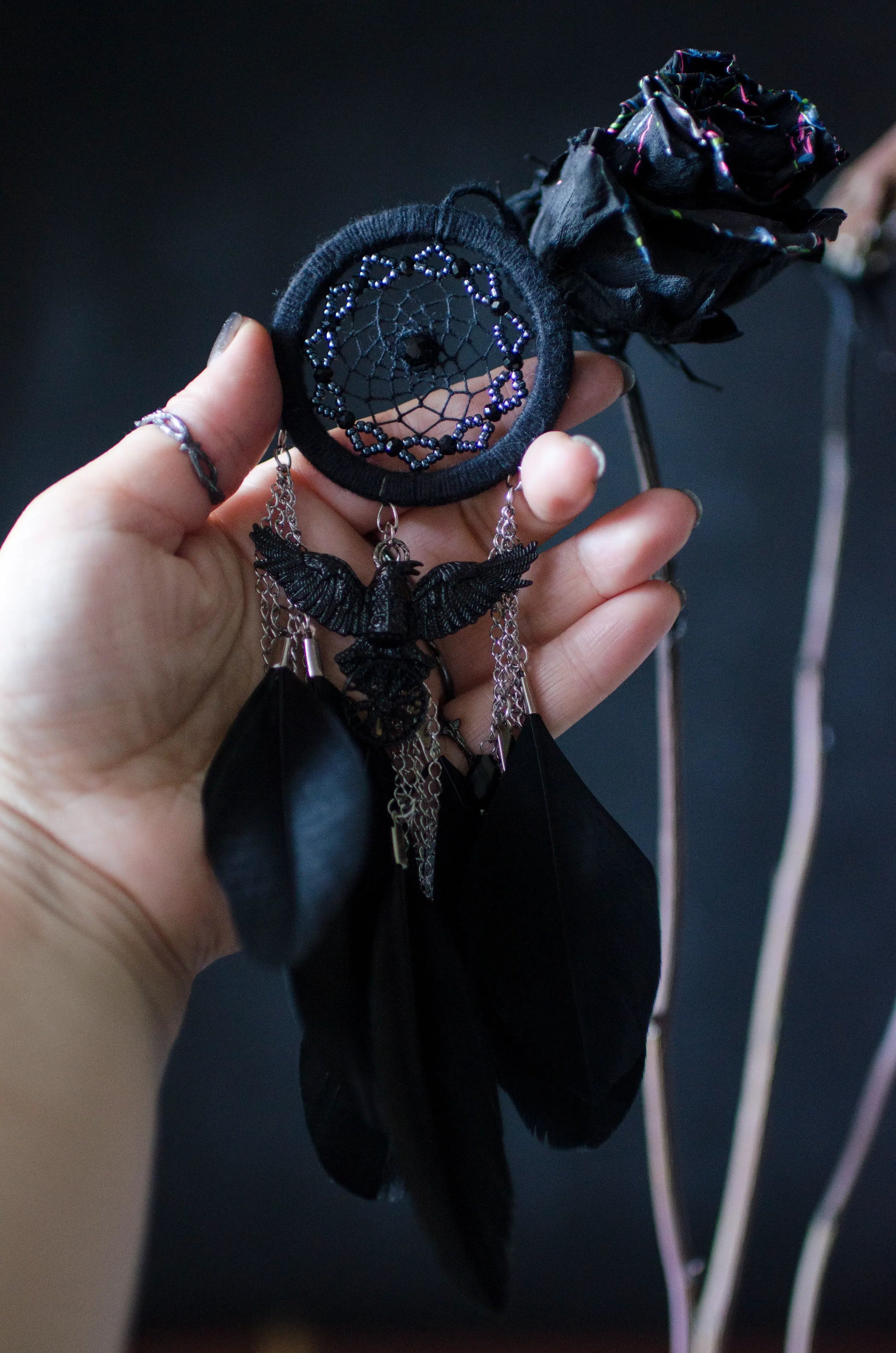 Handcrafted mini dream catcher with a black hoop and web adorned with purple beads, featuring a central raven charm with purple chains and black feathers. Ideal for gothic or bohemian decor.