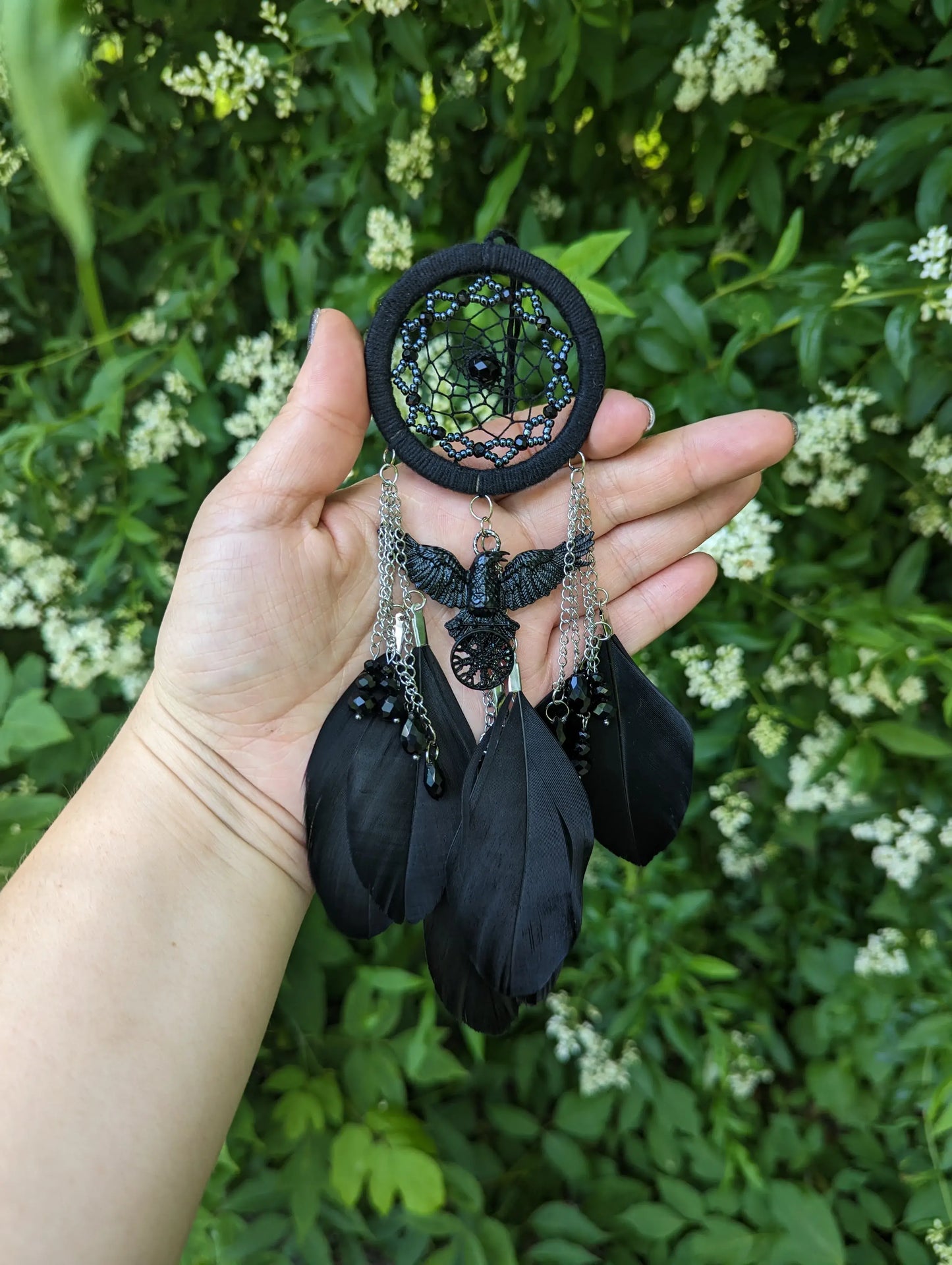 Handcrafted mini dream catcher with a black hoop and web adorned with purple beads, featuring a central raven charm with purple chains and black feathers. Ideal for gothic or bohemian decor.