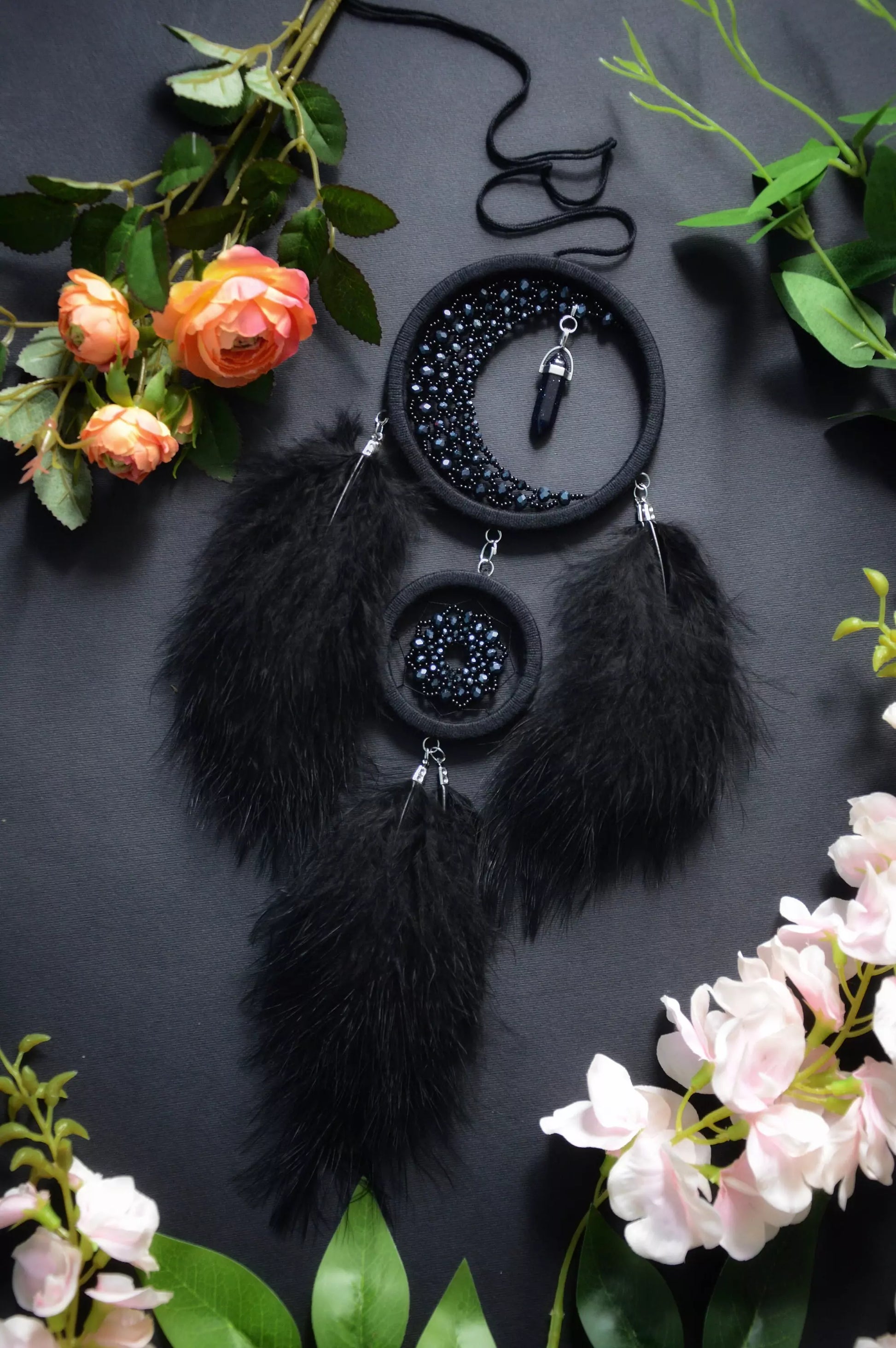 Handmade black crescent moon dreamcatcher adorned with black aventurine crystals, black beads, and soft black feathers, designed for boho and gothic decor, spiritual protection, and mystical ambiance in any space.