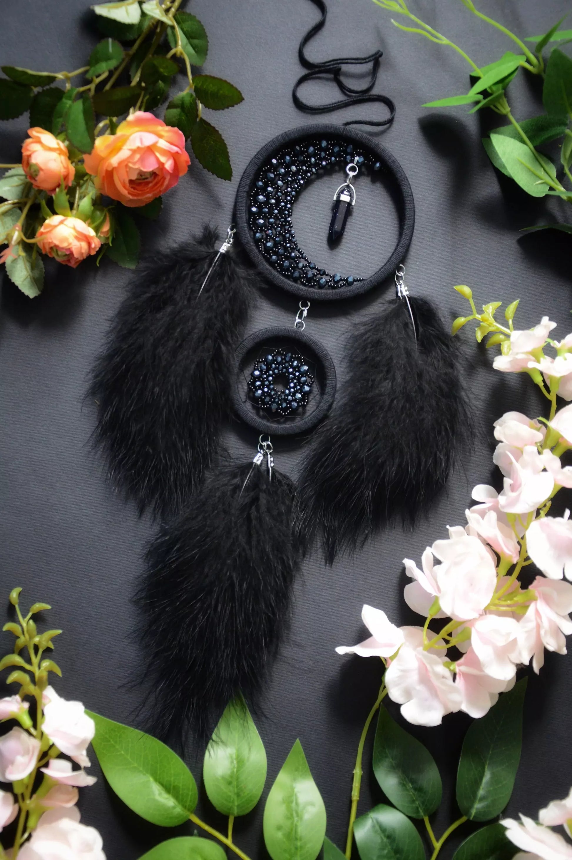 Handmade black crescent moon dreamcatcher adorned with black aventurine crystals, black beads, and soft black feathers, designed for boho and gothic decor, spiritual protection, and mystical ambiance in any space.