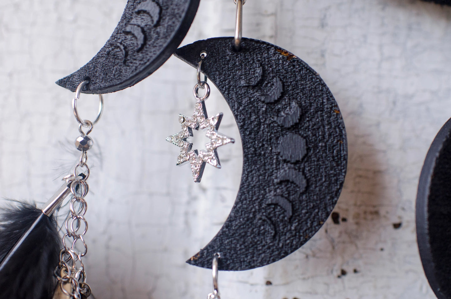 Handcrafted black dream catcher featuring a central web with black beads, adorned with five crescent moons and a central full moon, complemented by lush black feathers.