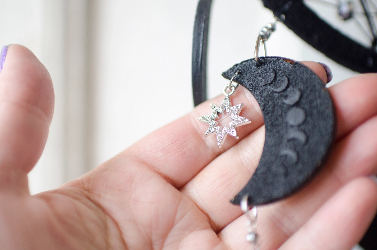 Handcrafted black dream catcher featuring a central web with black beads, adorned with five crescent moons and a central full moon, complemented by lush black feathers.