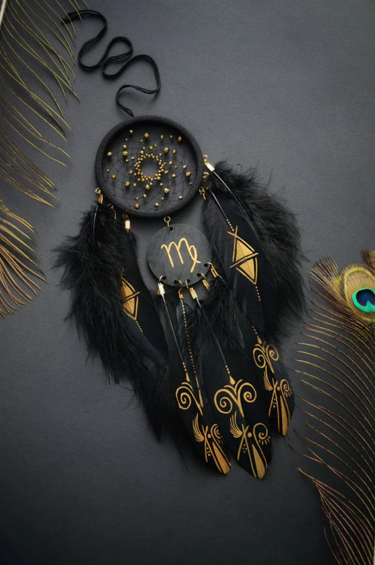 A black dream catcher with intricate gold beadwork and zodiac symbols, adorned with black feathers and golden geometric designs, paired with a blue dream catcher featuring peacock feathers and vibrant blue and gold detailing, both highlighting celestial and zodiac motifs.