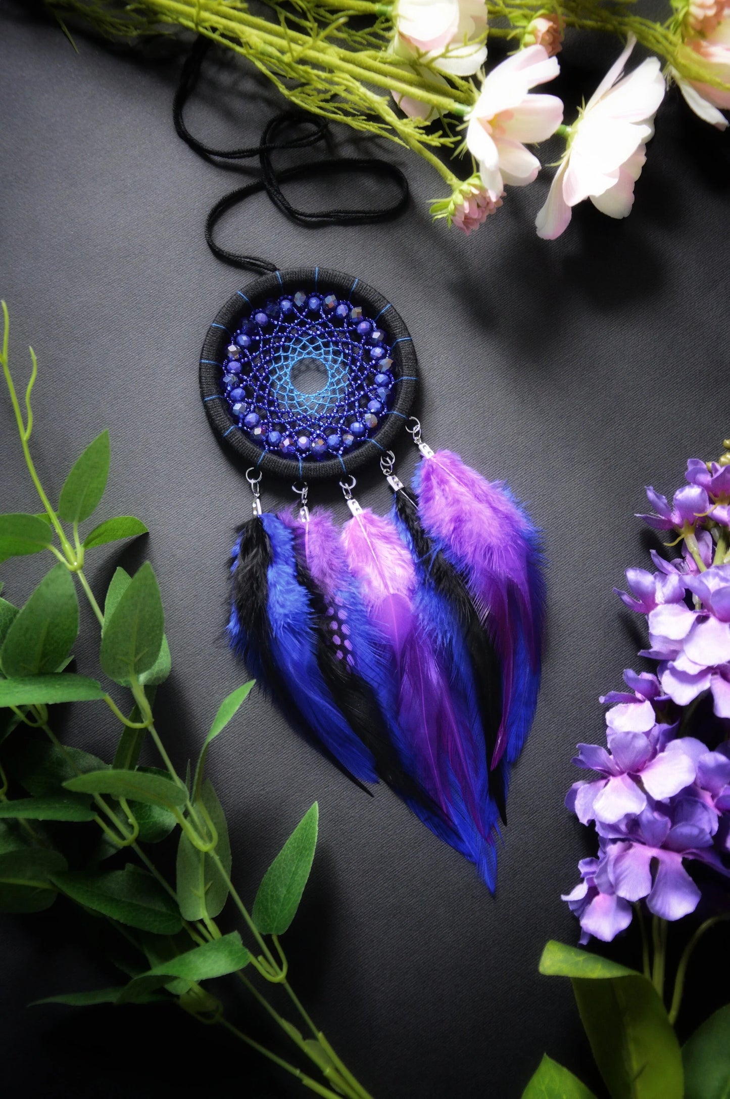 Handmade purple and blue dream catcher with intricate webbing, adorned with beads and vibrant purple and blue feathers, designed for boho wall decor and spiritual protection, perfect as a unique gift or a mystical home accent.