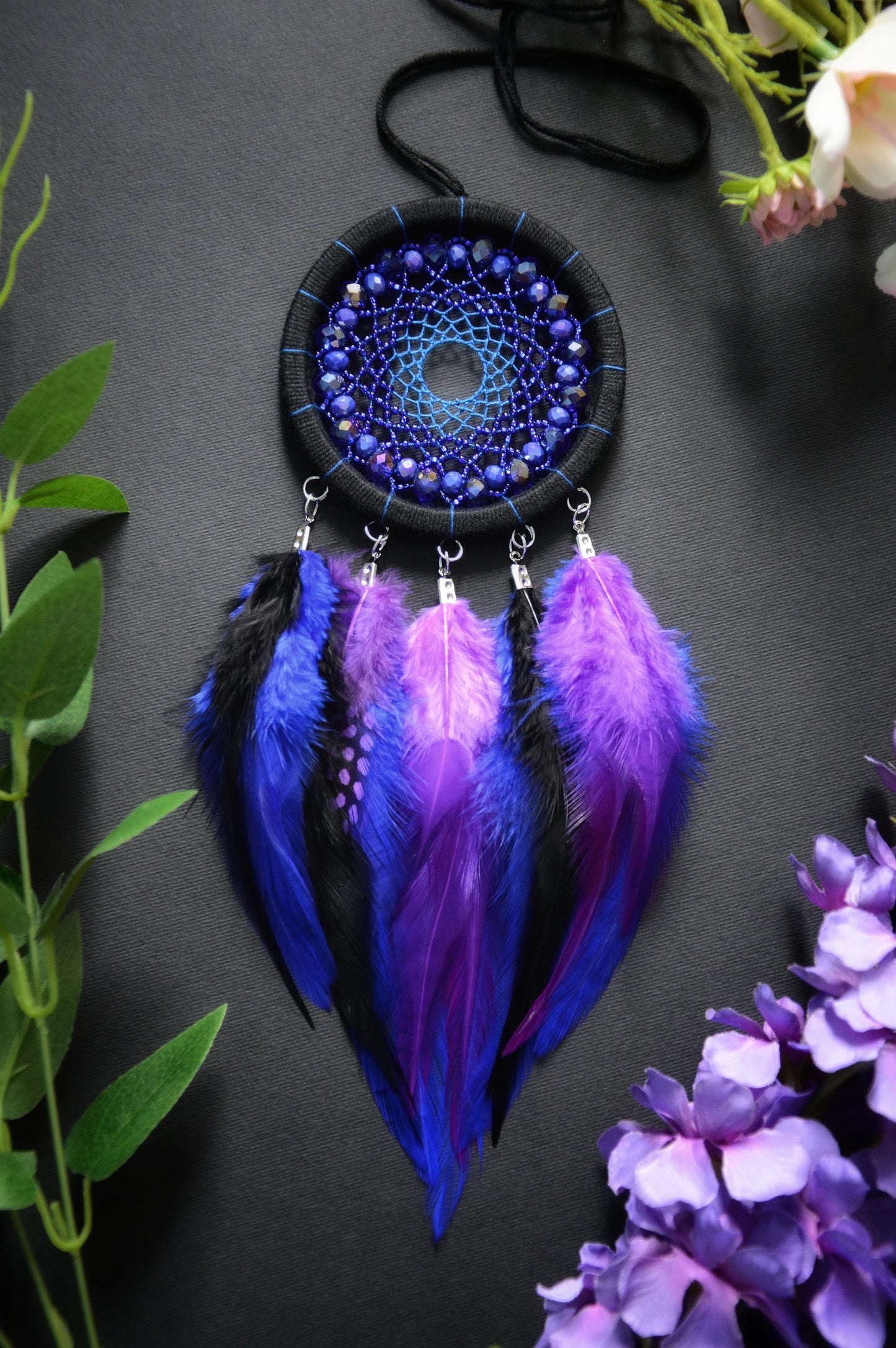 Handmade purple and blue dream catcher with intricate webbing, adorned with beads and vibrant purple and blue feathers, designed for boho wall decor and spiritual protection, perfect as a unique gift or a mystical home accent.