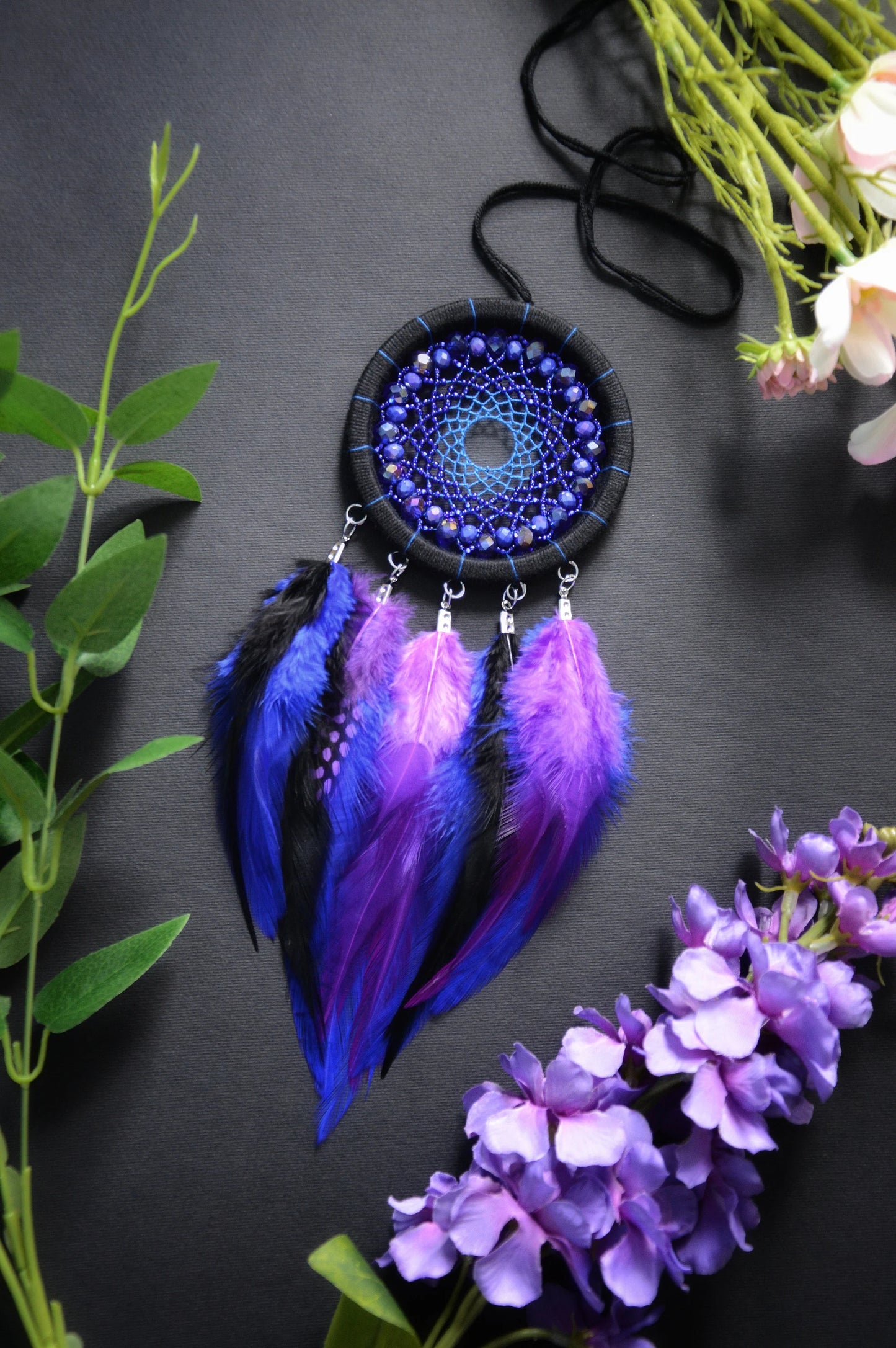 Handmade purple and blue dream catcher with intricate webbing, adorned with beads and vibrant purple and blue feathers, designed for boho wall decor and spiritual protection, perfect as a unique gift or a mystical home accent.