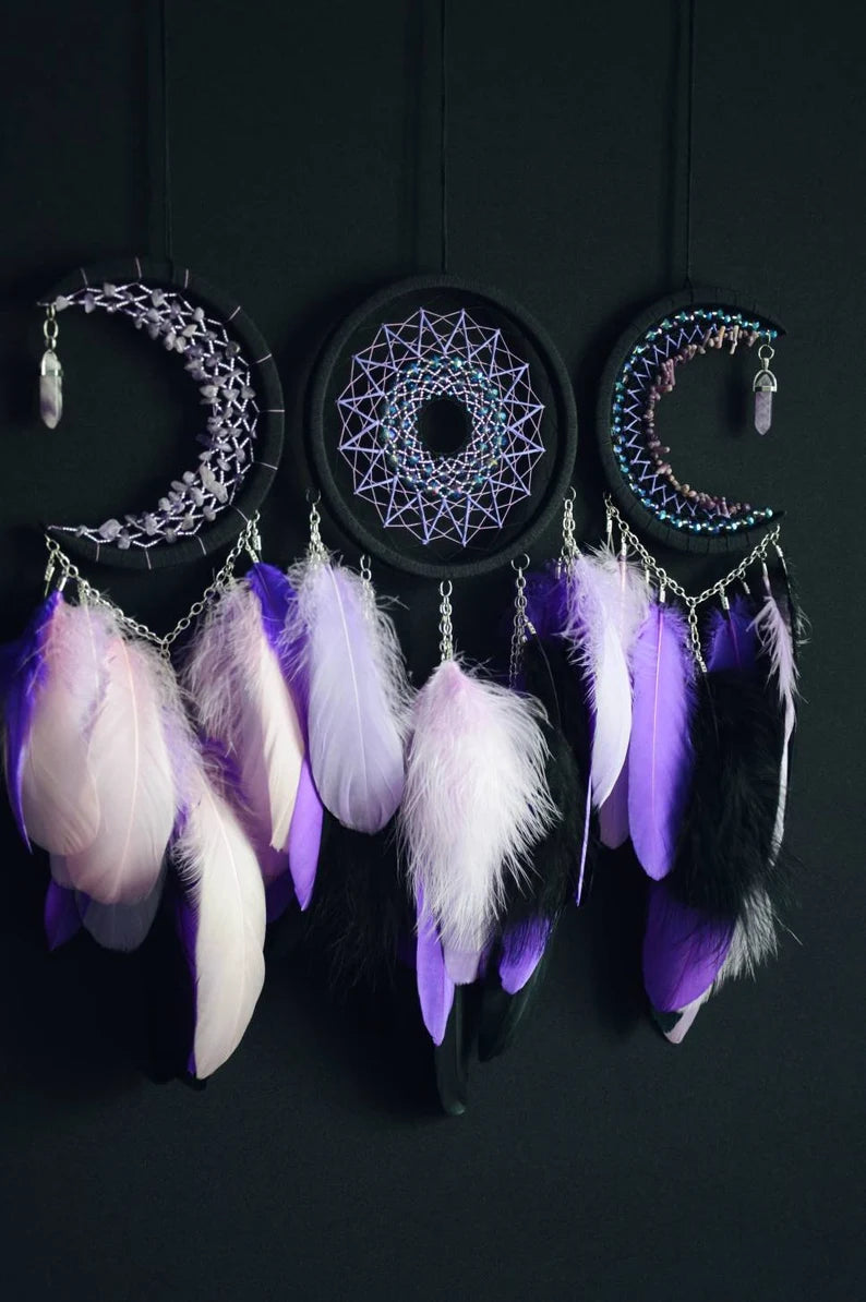 Handmade purple triple moon dreamcatcher set featuring intricate moon phase designs, adorned with purple and black feathers, amethyst crystal accents, and chain details. Perfect for celestial-inspired boho wall decor or spiritual meditation spaces.