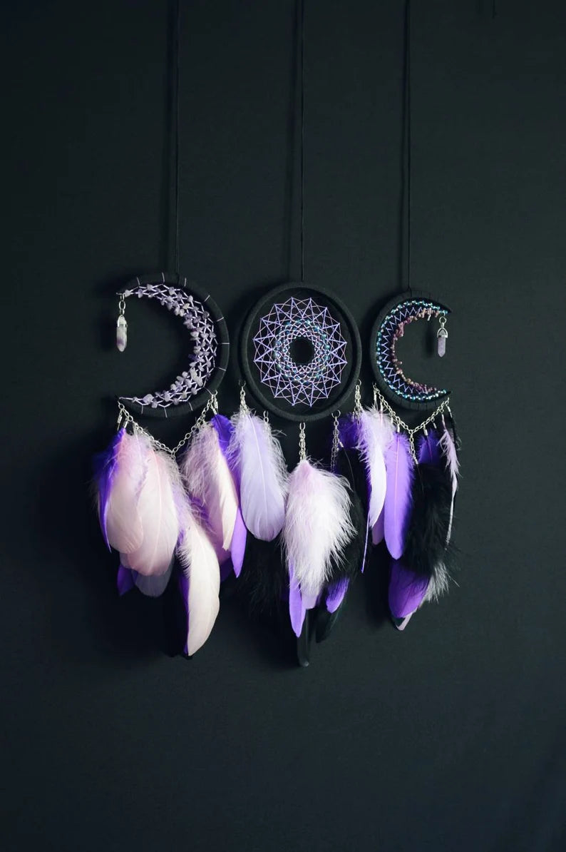 Handmade purple triple moon dreamcatcher set featuring intricate moon phase designs, adorned with purple and black feathers, amethyst crystal accents, and chain details. Perfect for celestial-inspired boho wall decor or spiritual meditation spaces.